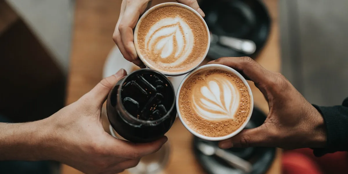 Overhead view of coffee cups with latte art on a warm table